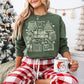 sweatshirt with a white holiday book-themed design and the phrase ‘All Booked for Christmas,’ styled flat lay with festive decor including pine branches, red berries, and cozy reindeer slippers.