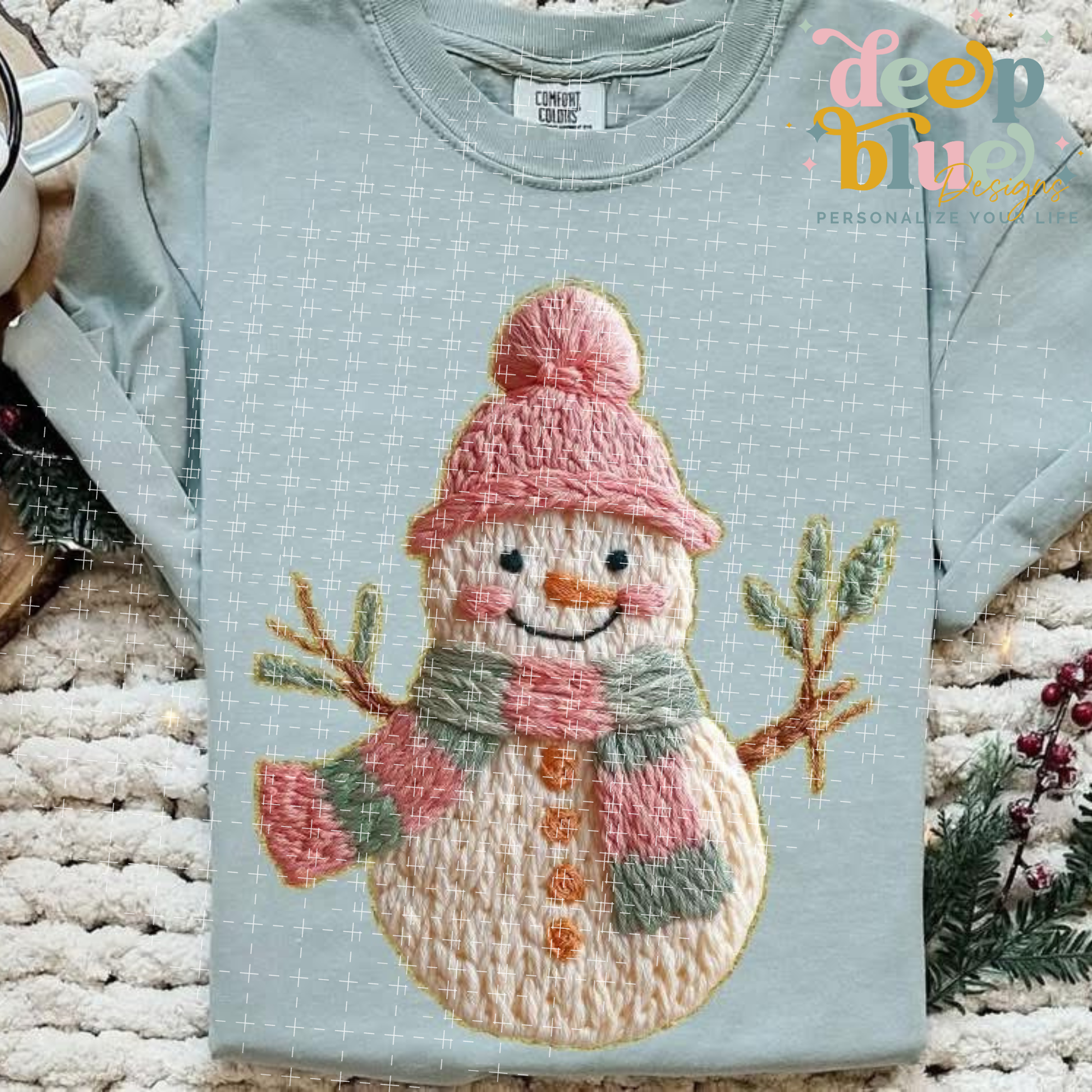 Light blue sweatshirt with a embroidered snowman design on a textured surface.