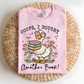 Pink t-shirt with a cartoon duck holding books and text on a woven mat