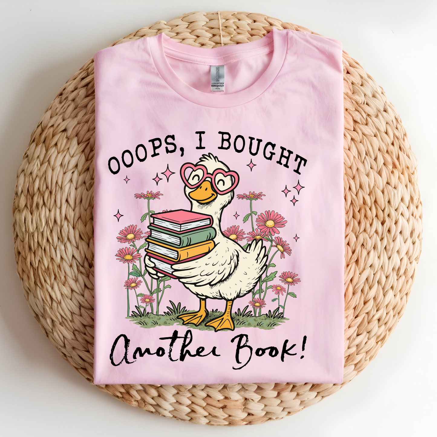 Pink t-shirt with a cartoon duck holding books and text on a woven mat