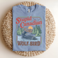 Blue t-shirt with 'Stupid Canadian' graphic design on a woven mat