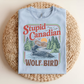 Light blue t-shirt with 'Stupid Canadian Wolf Bird' graphic on a woven mat
